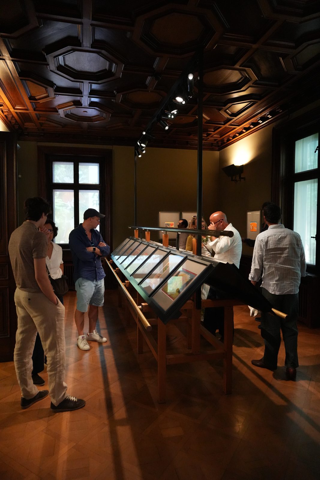 Visitors viewing paintings in the vitrines at Park-Villa Rieter